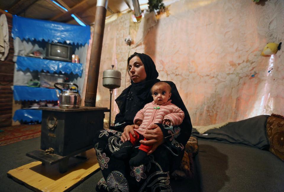 In this Tuesday, March 11, 2014 photo, Mervat, 31, speaks during an interview with The Associated Press as she holds her 9-month-old daughter Shurouk inside their tent at a camp for Syrian refugees in Kab Elias, in Lebanon's Bekaa Valley. Trapped in her northern Syrian village by fighting, Mervat watched her newborn baby progressively shrink. Her daughter’s dark eyes seemed to grow bigger as her face grew more skeletal. Finally, Mervat escaped to neighboring Lebanon, and a nurse told her the girl was starving. Such stark malnutrition was rare in Syria in the past, but as the country’s conflict enters its fourth year, international aid workers fear malnutrition is rising among children in Syria and among refugees amid the collapse in the health care system.(AP Photo/Bilal Hussein)