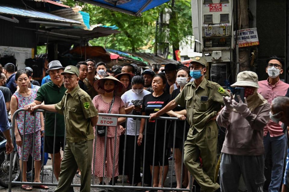 Residents stand behind a barrier near the site of a major fire at an apartment block in Hanoi (AFP via Getty Images)