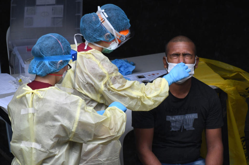 A healthcare worker collects a nasal swab sample from a migrant worker testing for the COVID-19 novel coronavirus at a dormitory in Singapore on April 27, 2020. | Roslan Rahman—AFP/Getty Images