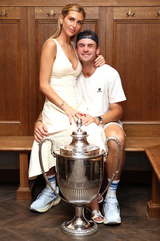 <p>Clive Brunskill/Getty</p> Tommy Paul and Paige Lorenze pose for a photo with the cinch Championships 2024 winners trophy on Day Seven of the cinch Championship at The Queen's Club on June 23, 2024 in London, England.