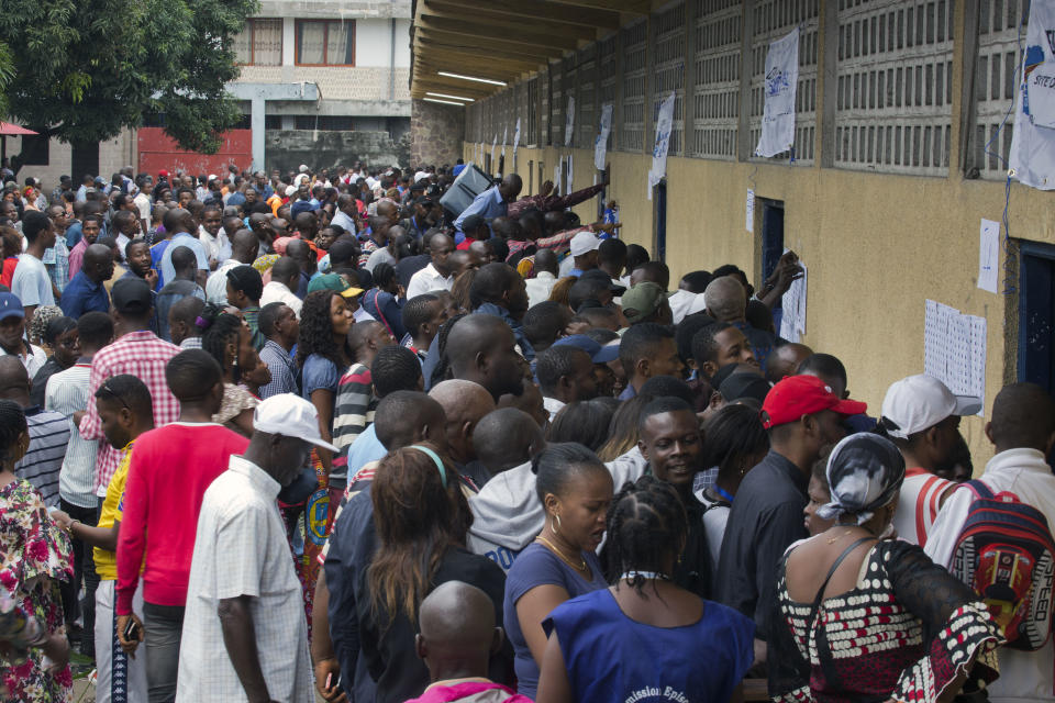 Hundreds of Congolese voters who have been waiting at the St. Raphael school in the Limete district of Kinshasa Sunday Dec. 30, 2018, storm the polling stations after the voters listings were finally posted five hours after the official start of voting. Forty million voters are registered for a presidential race plagued by years of delay and persistent rumors of lack of preparation. (AP Photo/Jerome Delay