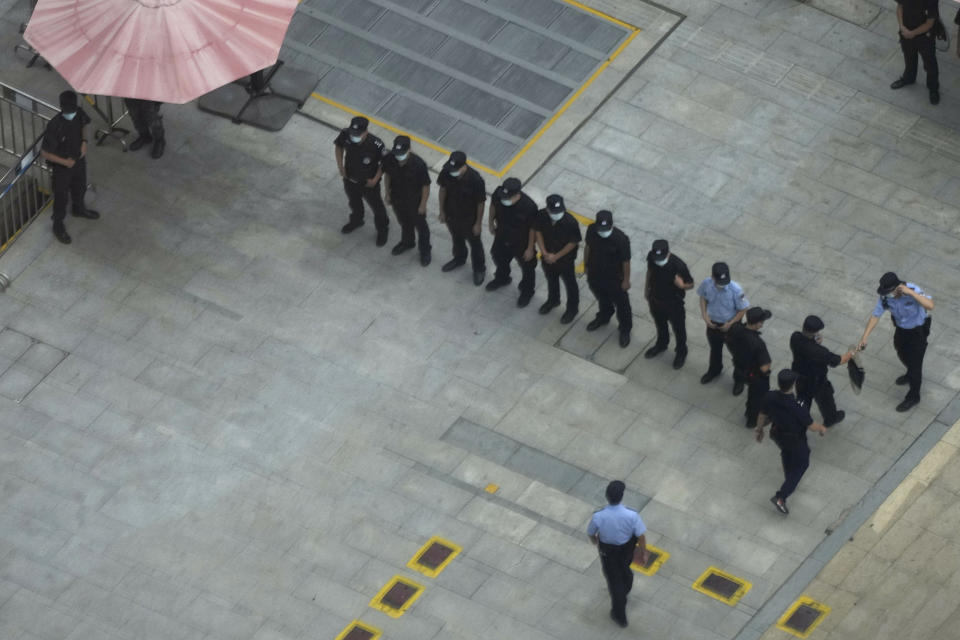 Police officers and security guards prepare for duty outside the headquarters for Evergrande in Shenzhen in southern China, Thursday, Sept. 23, 2021. The Chinese real estate developer whose struggle to avoid defaulting on billions of dollars of debt has rattled global markets says it will pay interest due Thursday to bondholders in China but gave no sign of plans to pay on a separate bond abroad. (AP Photo/Ng Han Guan)