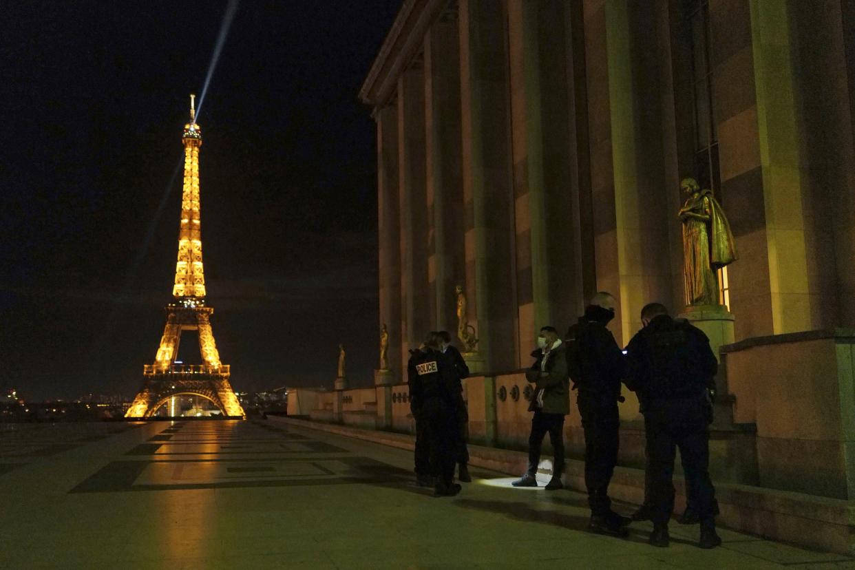 French police officers stop a person on the Trocadero near the Eiffel Tower as they enforce a curfew in Paris, France, Tuesday, Dec. 15, 2020. France on Tuesday is lifting a lockdown imposed on Oct. 30 but starts a new curfew at 20h00, local time, as infections are still high.