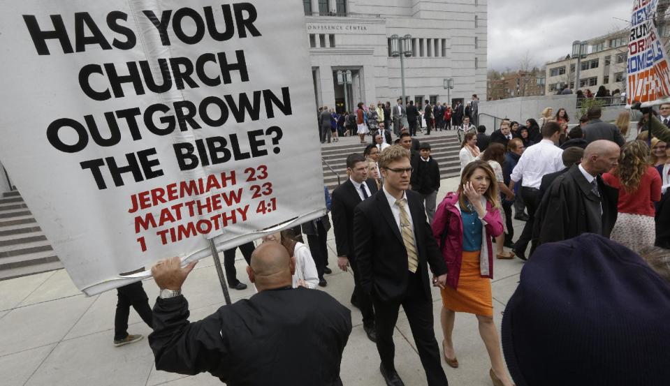 People walk pass a unidentified protester on their way from the Conference Center during opening session of the two-day Mormon church conference Saturday, April 5, 2014, in Salt Lake City. More than 100,000 Latter-day Saints are expected in Salt Lake City this weekend for the church's biannual general conference. Leaders of The Church of Jesus Christ of Latter-day Saints give carefully crafted speeches aimed at providing members with guidance and inspiration in five sessions that span Saturday and Sunday. They also make announcements about church statistics, new temples or initiatives. In addition to those filling up the 21,000-seat conference center during the sessions, thousands more listen or watch around the world in 95 languages on television, radio, satellite and Internet broadcasts. (AP Photo/Rick Bowmer)