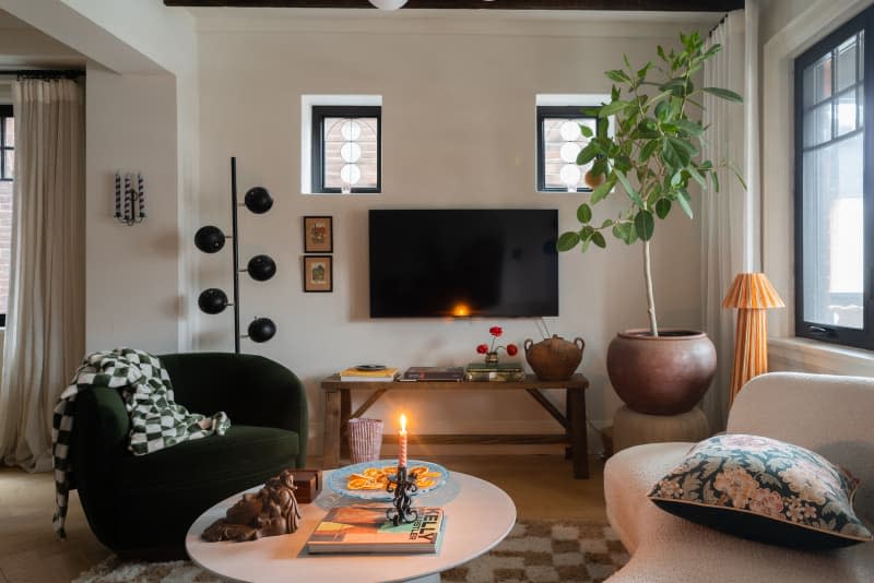 White living room with black accent and large circled fabric couch opposite to a black chair.