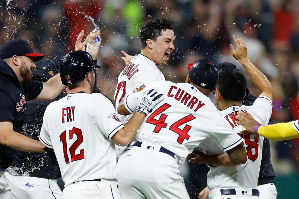 Cleveland Guardians' Will Brennan, center, is mobbed by teammates after getting the winning hit to defeat the Houston Astros in a 14-inning game Friday in Cleveland.