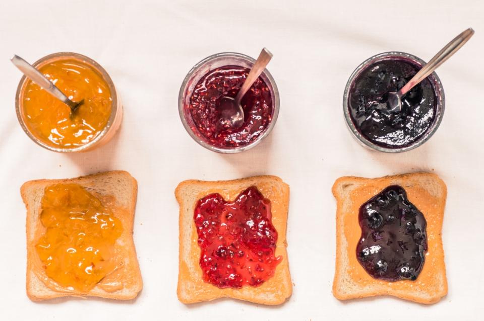 Toast sandwiches with peanut butter and jam raspberry, blueberries, orange top view