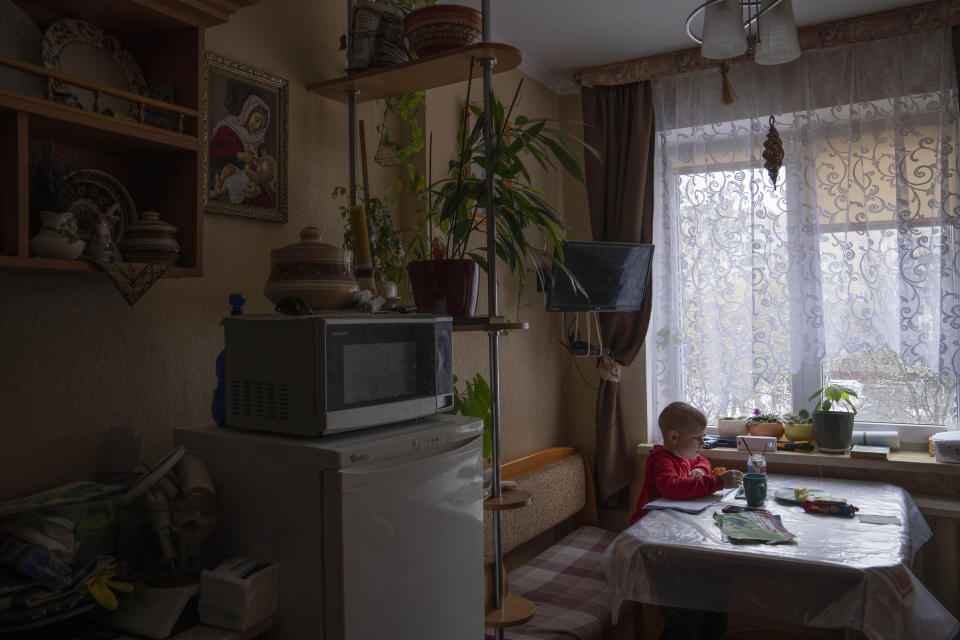 Nazar, paints in the kitchen of an apartment given to his family by a cousin after they fled their home in Kyiv, in Lviv, western Ukraine, Sunday, April 3, 2022. The family wants to stay in Ukraine, but they have no long-term plan. (AP Photo/Nariman El-Mofty)