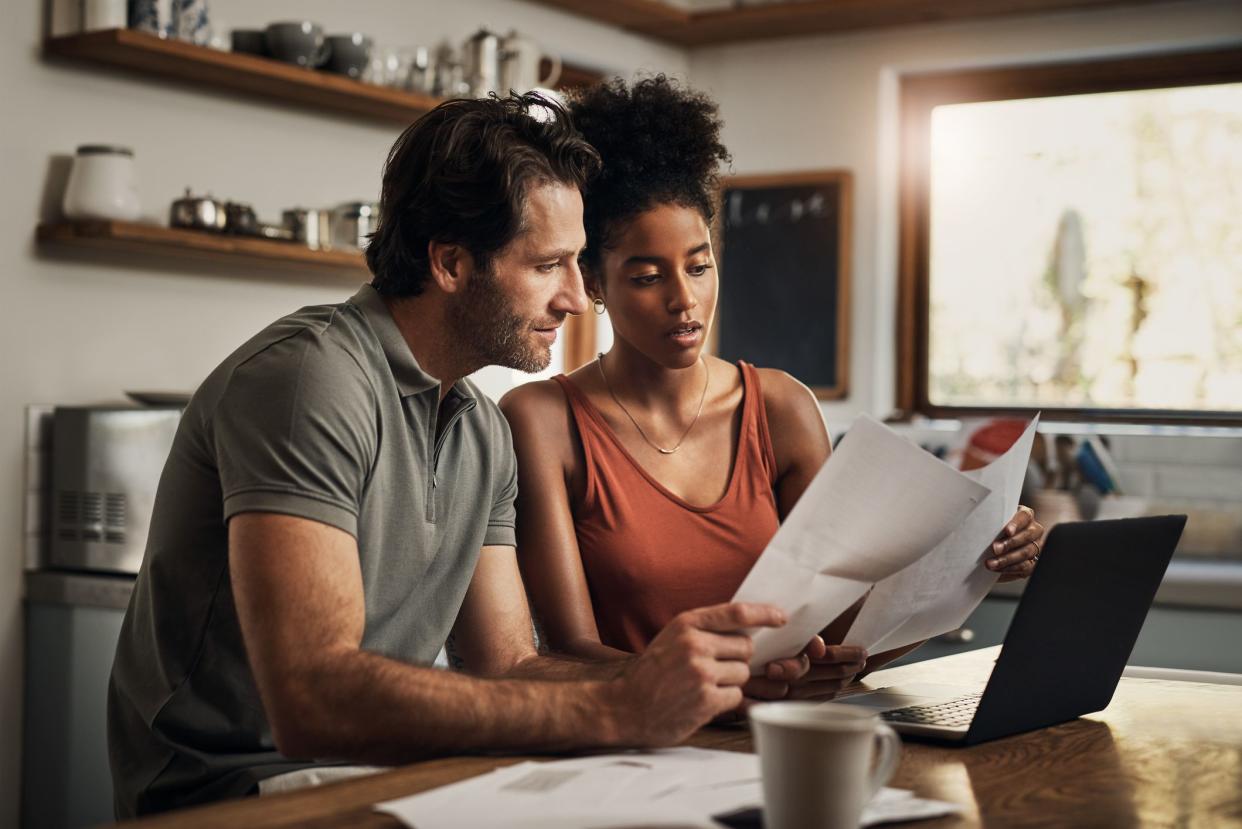 Cropped shot of an affectionate young couple going through paperwork while doing their budget at home