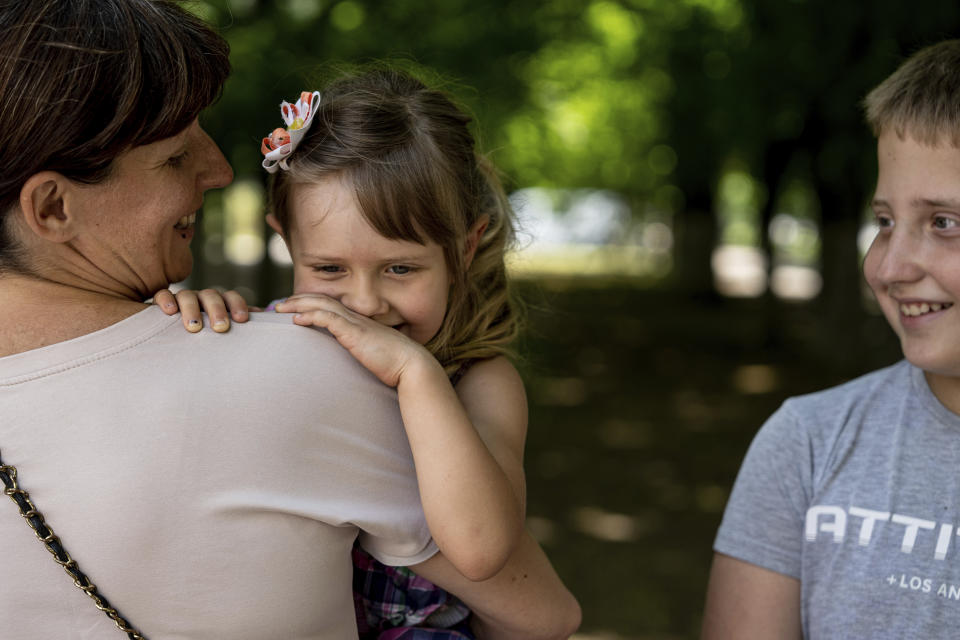 Kateryna Krupych sostiene en brazos a su hija Masha, de 4 años, mientras posa para una fotografía junto a su hijo Maksim, en Jersón, Ucrania, el 13 de junio de 2023. Krupych y sus hijos fueron rescatados luego de que tuviesen que abandonar su casa en la isla de Chaika, en la zona gris entre las líneas del frente. (AP Foto/Evgeniy Maloletka)