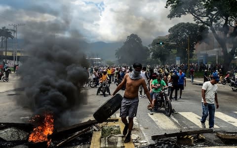 Anti-government activists build a barricade in Venezuela's third city, Valencia - Credit: AFP