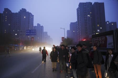 People wait for the bus to take them to Beijing from Yanjiao, Hebei province, China, November 13, 2015.
