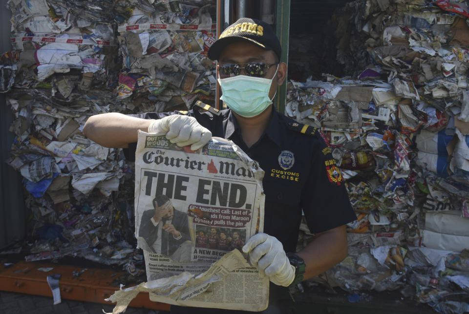 Indonesian custom officers show off the front of a foreign newspaper amoung waste found in a container at the Tanjung Perak port in Surabaya, East Java, Indonesia, Tuesday, July 9, 2019. Indonesia is sending dozens of containers of imported waste back to Western nations after finding it was contaminated with used diapers, plastic and other materials, adding to a growing backlash in Southeast Asia against being a dumping ground for the developed world's rubbish. (AP Photo)