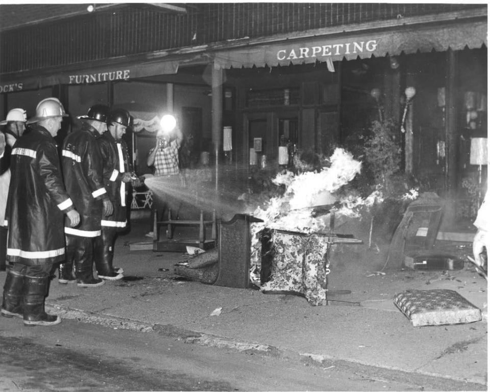 Firefighters douse the flames of burning furniture outside Sandock's Furniture Store on July 25, 1967, the first of three nights of rioting in South Bend.