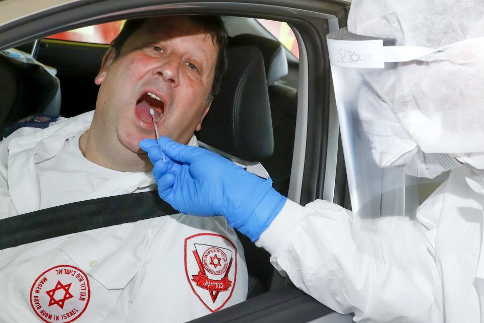 Israeli medical personnel demonstrate the drive through testing at the Israeli Magen David Adom (MDA) national emergency service drive through complex for COVID-19 testing in Hayarkon Park's Rokach blvd parking lot  in the coastal city of Tel Aviv on March 20, 2020. - The complex, which will open up in other cities, will allow individuals to arrive at the drive-through with their vehicle and get tested while still sitting in the car, the MDA reported. (Photo by JACK GUEZ / AFP) (Photo by JACK GUEZ/AFP via Getty Images)