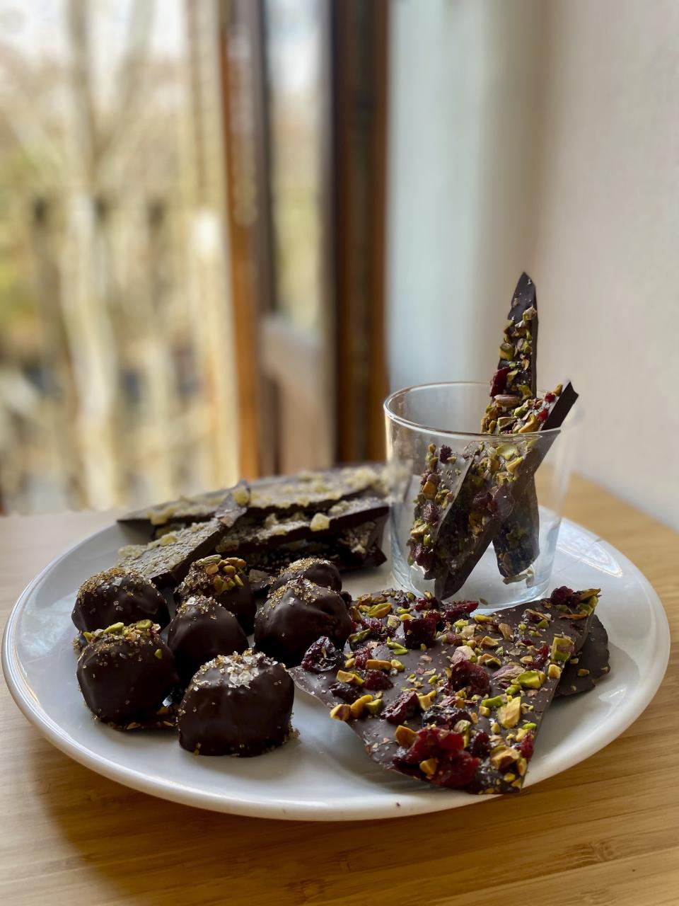 This image shows a plate of chocolate truffles and chocolate bark. Rather than spending on store-bought chocolates for Valentine’s Day, make them together as a fun way to spend the evening with your Valentine. (Albert Stumm via AP)