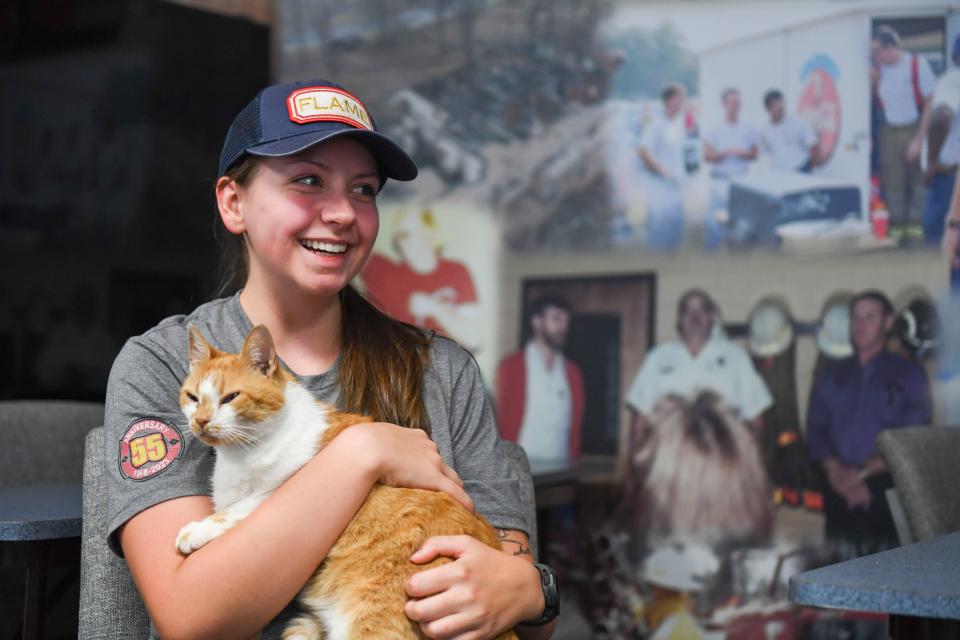 Gina Thompson, 22, fire fighter and EMT at Belmont Fire Department, holds Flame at the fire station where he lives on Wednesday, Aug. 9, 2023. Flame has lived at the station for nearly a decade. Thompson, Flame's caretaker, will take him home after his retirement.