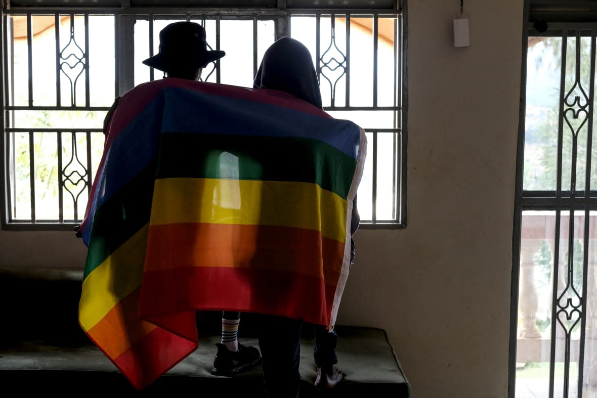 A gay Ugandan couple cover themselves with a pride flag as they pose for a photograph in Uganda on March 25, 2023. Uganda’s president Yoweri Museveni has signed into law tough new anti-gay legislation supported by many in the country but widely condemned by rights activists and others abroad, it was announced Monday, May 29, 2023. (AP Photo, File)