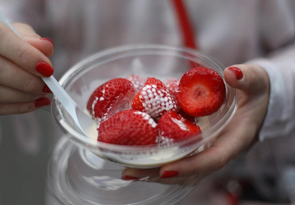 A visitor enjoys a bowl of strawberries and cream at the Wimbledon Championships (Philip Toscano/PA) (PA Archive)