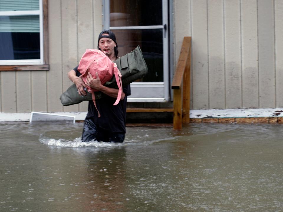 A man carries belongings through floodwaters from a home in Bridgewater, Vt., Monday, July 10, 2023. Heavy rain drenched part of the Northeast, washing out roads, forcing evacuations and halting some airline travel.