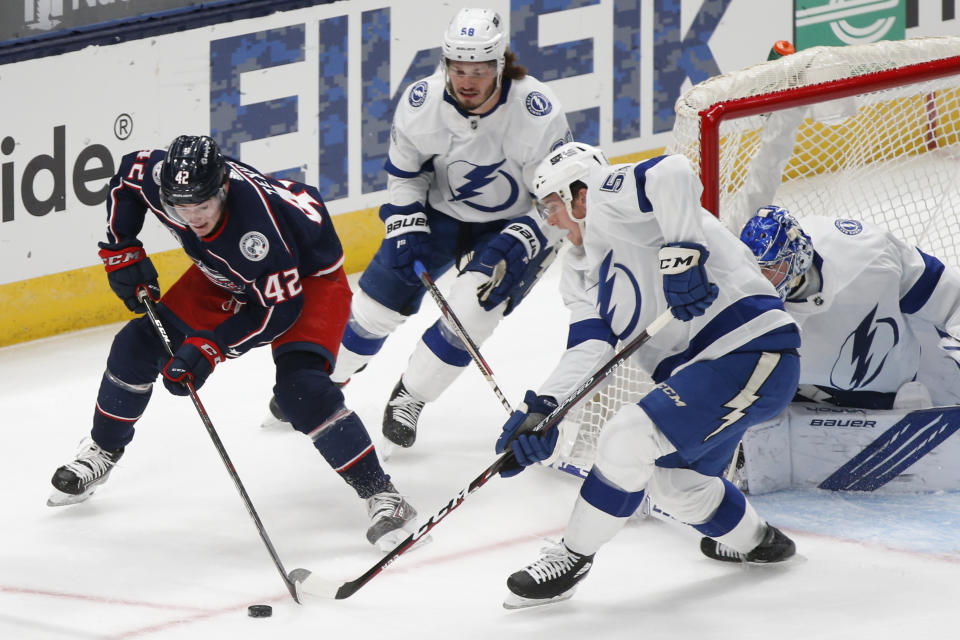 Columbus Blue Jackets' Alexandre Texier, left, of France, looks for an open shot as Tampa Bay Lightning's Mikhail Sergachev, center, of Russia, and Callan Foote defend during the first period of an NHL hockey game Saturday, Jan. 23, 2021, in Columbus, Ohio. (AP Photo/Jay LaPrete)