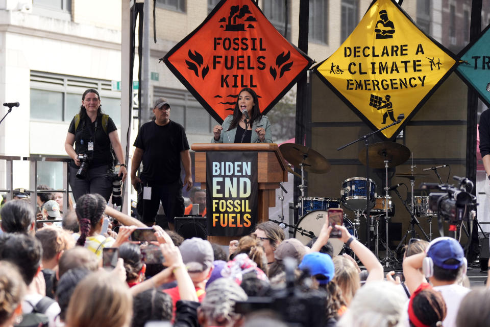 New York Representative Alexandria Ocasio-Cortez speaks at a podium at a rally following the March to End Fossil Fuels. 