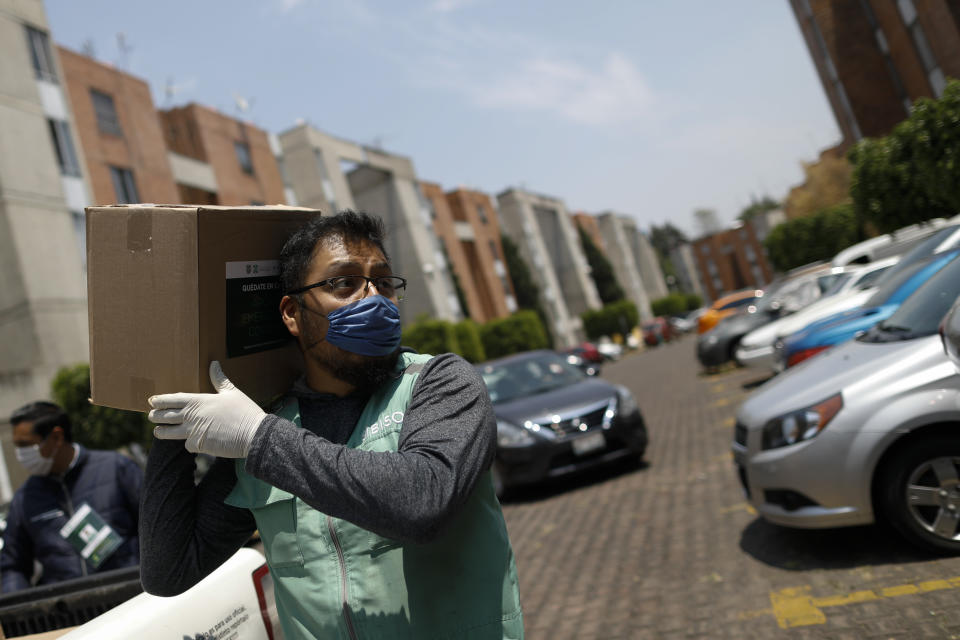 A city workers carries a food supply kit during home deliveries to households with a member suffering from symptoms of COVID-19, in the Coyoacan district of Mexico City, Thursday, April 9, 2020. To help halt the spread of the new coronavirus, the Mexican megalopolis is making home deliveries to households with a symptomatic person, providing kits containing food staples, face masks, gloves, antibacterial gel, paracetamol, a thermometer, and benefits cards with a balance of 1000 pesos (around $42). (AP Photo/Rebecca Blackwell)