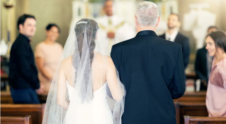 A father walks his daughter down the aisle during her wedding.