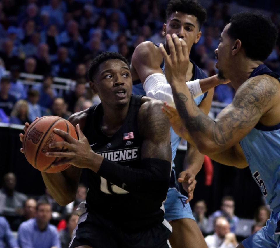 PC's Emmitt Holt tries to drive past URI’s Jacob Toppin, center, and Mekhi Long during their 2019 matchup at the Ryan Center.