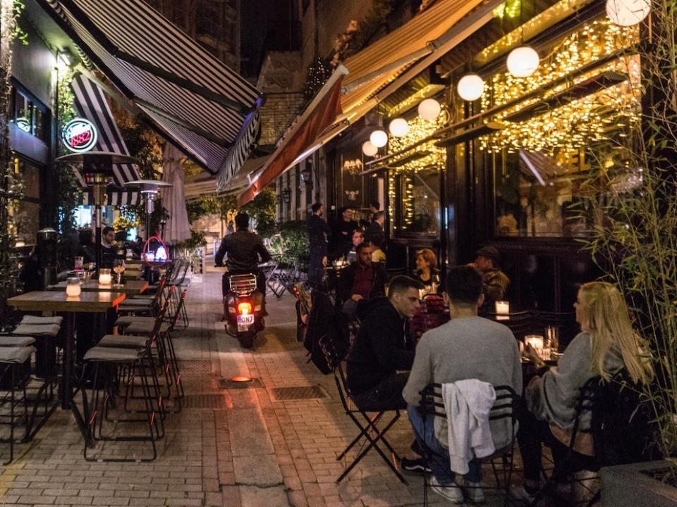 people sitting outside bars in athens greece