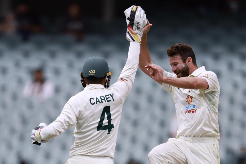 Australia's Alex Carey, left, and Michael Neser celebrate after they combined to take the wicket of the West Indies' Roston Chase on the fourth day of their cricket test match in Adelaide, Sunday, Nov. 11, 2022. (AP Photo/James Elsby)