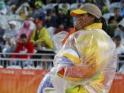 2016 Rio Olympics - Beach Volleyball - Men's Preliminary - Beach Volleyball Arena - Rio de Janeiro, Brazil - 10/08/2016. A volunteer bundles up against the rain during beach volleyball. REUTERS/Ruben Sprich