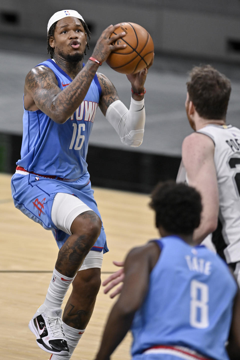 Houston Rockets' Ben McLemore (16) shoots against San Antonio Spurs' Jakob Poeltl, right, as Rockets forward Jae'Sean Tate looks on during the second half of an NBA basketball game, Saturday, Jan. 16, 2021, in San Antonio. (AP Photo/Darren Abate)