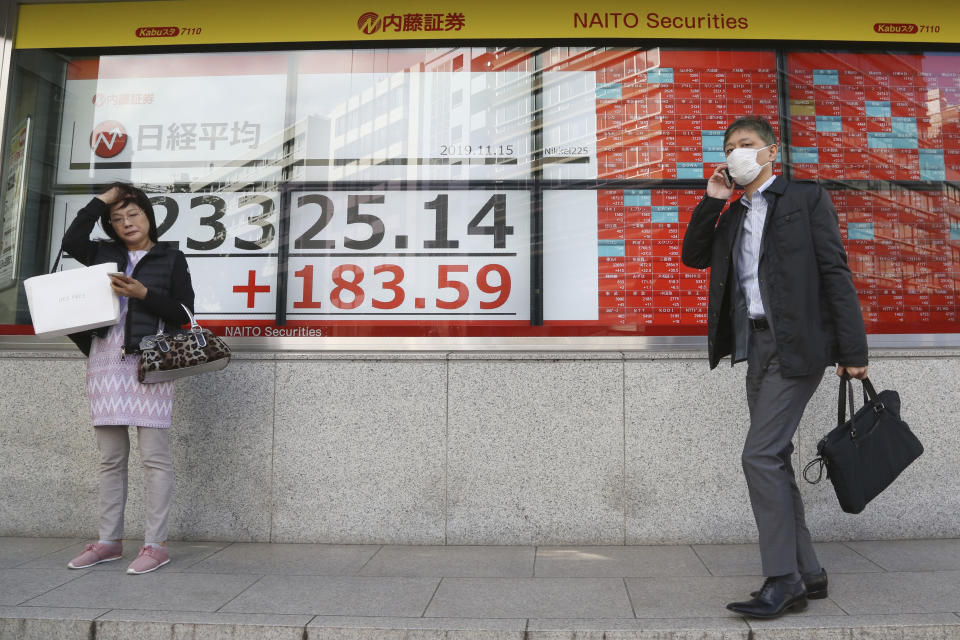 People stand by an electronic stock board of a securities firm in Tokyo, Friday, Nov. 15, 2019. Shares are higher in Asia after U.S. officials said China and the U.S. were getting close to an agreement to cool tensions over trade.(AP Photo/Koji Sasahara)