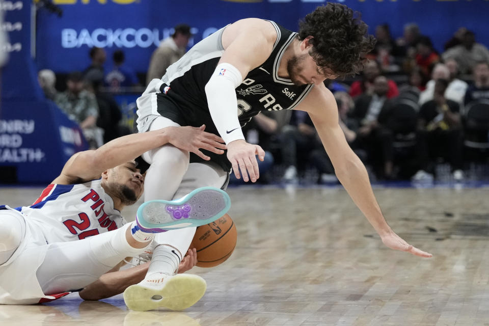 Detroit Pistons forward Kevin Knox II (24) and San Antonio Spurs forward Cedi Osman (16) reach for the loose ball during the first half of an NBA basketball game, Wednesday, Jan. 10, 2024, in Detroit. (AP Photo/Carlos Osorio)