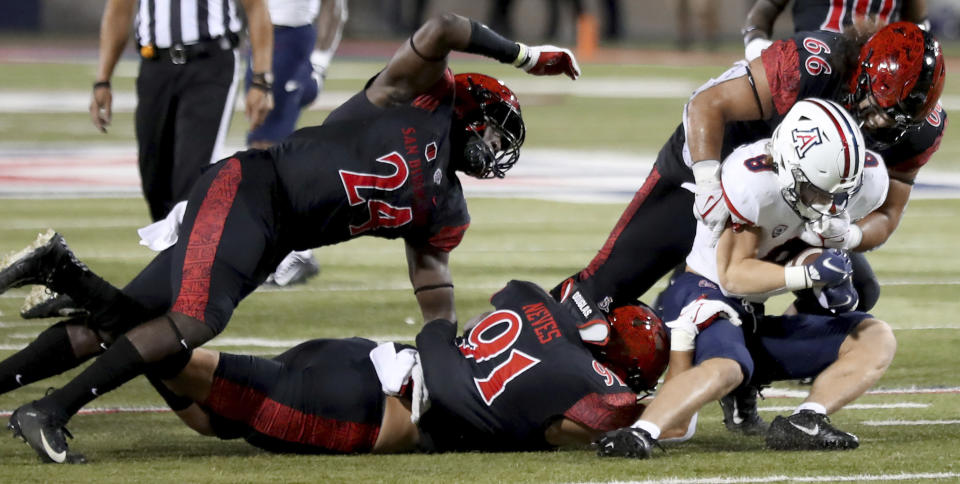 Arizona running back Drake Anderson (8) gets swarmed behind the line of scrimmage by San Diego State linebacker Segun Olubi (24), left, defensive lineman Kahi Neves (91) and defensive lineman Jonah Tavai (66) in the second half of the NCAA college football game in Tucson, Ariz., Saturday, Sept. 11, 2021. (Kelly Presnell/Arizona Daily Star via AP)