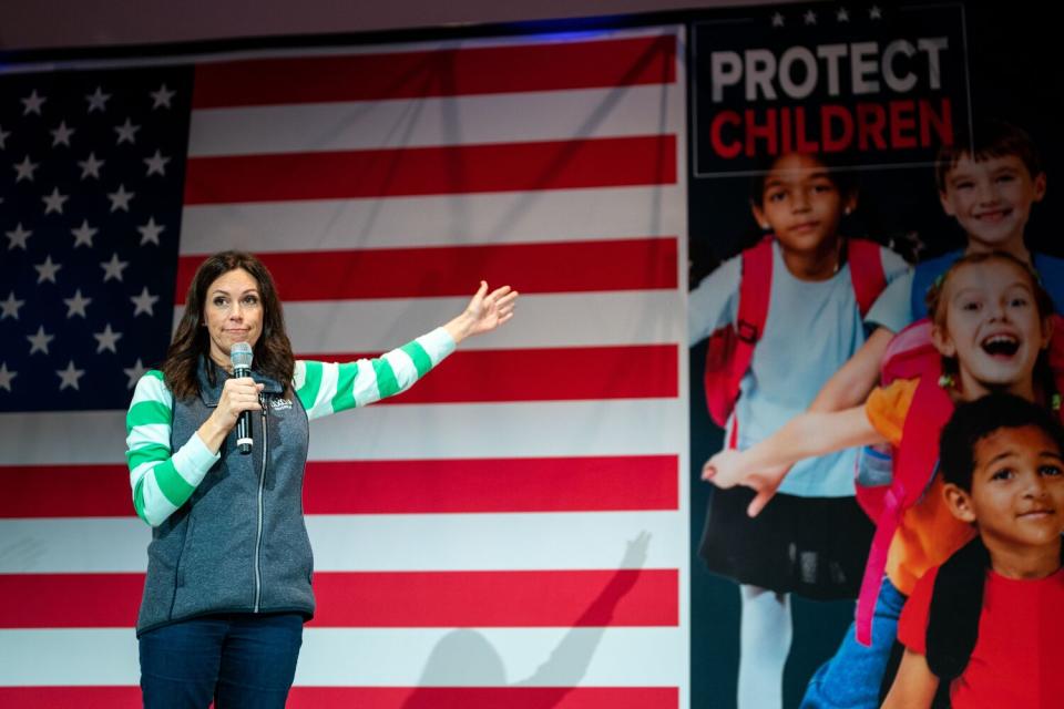 A woman stands near a blown-up photo of kids and a big American flag.