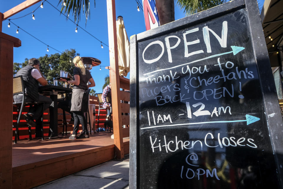 FILE - In this Friday, Dec. 18, 2020, file photo, a sign saying "Open," is displayed outside a restaurant along the Coast Highway 101 in Encinitas, Calif., amid the coronavirus pandemic. Congress’ $900 billion pandemic relief package, which passed Monday, Dec. 21, 2020, includes a $600 direct stimulus payment to most Americans and a new round of subsidies for hard-hit businesses, restaurants and theaters. (AP Photo/Ringo H.W. Chiu, File)