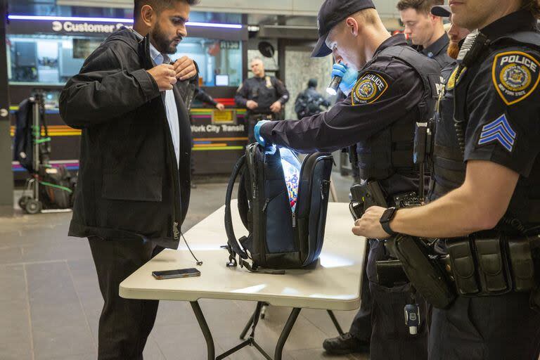 Miembros de las Fuerzas Armadas, incluida la Guardia Nacional, patrullan el sistema de metro en Penn Station mientras los agentes de policía revisan las maletas de los viajeros en Nueva York el jueves 7 de marzo de 2024