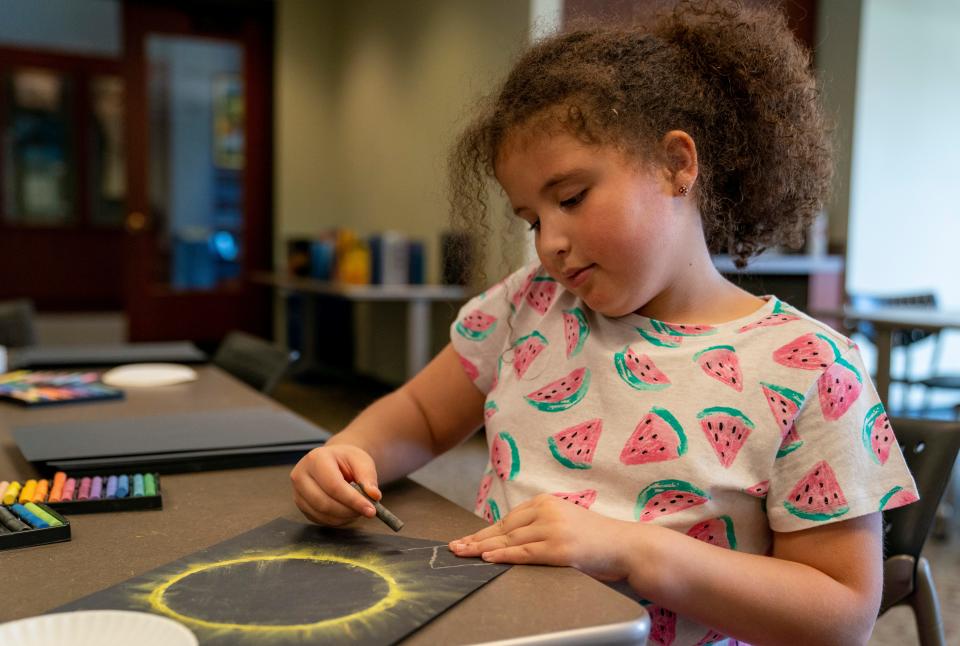 Josie Johnson draws the eclipse with chalk during the Evansville Vanderburgh Public Library SolarFest Saturday, March 30, 2024.