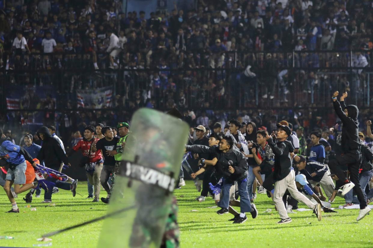 Soccer fans enter the pitch during a clash between teams' supporters at Kanjuruhan Stadium in Malang, East Java, Indonesia on Saturday. More than 100 people died.