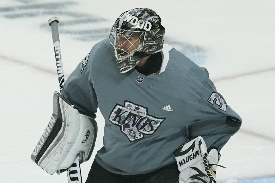 A puck catches the sleeve of Los Angeles Kings goaltender Jonathan Quick (32) as he warms up before an NHL hockey game against the Anaheim Ducks Wednesday, April 28, 2021, in Los Angeles. (AP Photo/Ashley Landis)