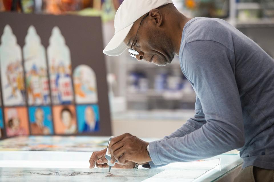 Memphis artist Lonnie Robinson traces his artwork onto glass with finely ground glass in a binder, used for lining and shading, while working at Pearl River Glass Studio in Jackson on Wednesday, Feb. 15, 2023. Pearl River Glass is doing restoration work on the windows of the historic Clayborn Temple in Memphis.