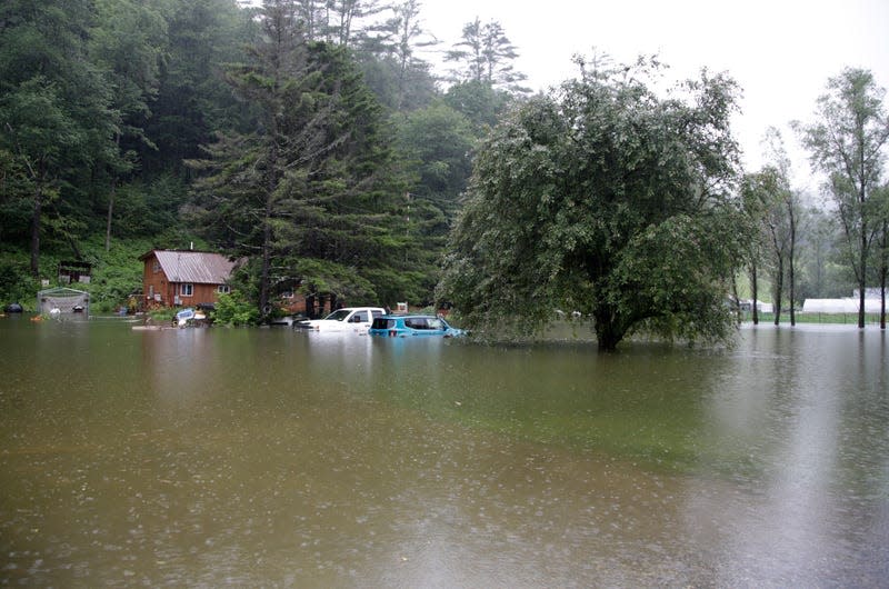 Floodwaters rise in Bridgewater, Vt., on Monday, July 10, 2023, submerging parked vehicles and threatening homes near the Ottauquechee River.