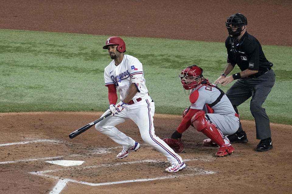 CORRECTS DAY TO MONDAY INSTEAD OF SATURDAY - Texas Rangers' Marcus Semien follows through on a run-scoring single as St. Louis Cardinals catcher Willson Contreras and umpire Pat Hoberg look on in the second inning of a baseball game, Monday, June 5, 2023, in Arlington, Texas. Ezequiel Duran scored on the hit. (AP Photo/Tony Gutierrez)