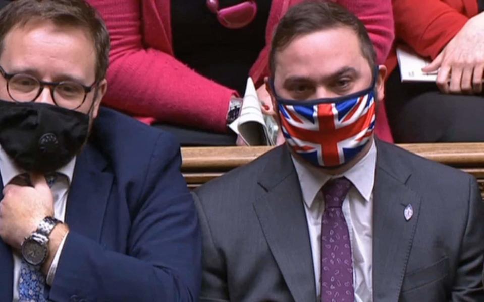 Christian Wakeford sat opposite Boris Johnson in the Commons wearing a Union Flag face mask during PMQs - PRU/AFP/via Getty Images