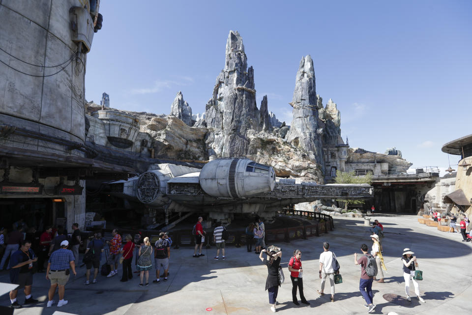 Park visitors walk near the entrance to the Millennium Falcon Smugglers Run ride during a preview of the Star Wars themed land, Galaxy's Edge in Hollywood Studios at Disney World, Tuesday, Aug. 27, 2019, in Lake Buena Vista, Fla. The attraction will open Thursday to park guests. (AP Photo/John Raoux)