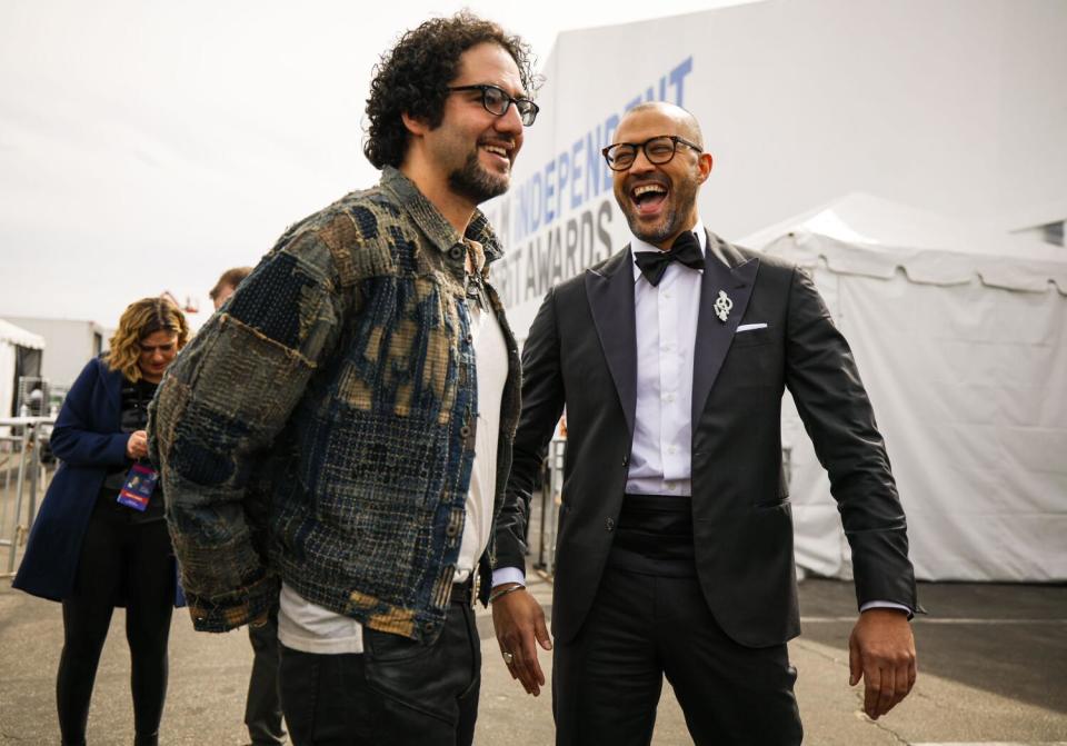 Two men stand smiling outside a large white tent