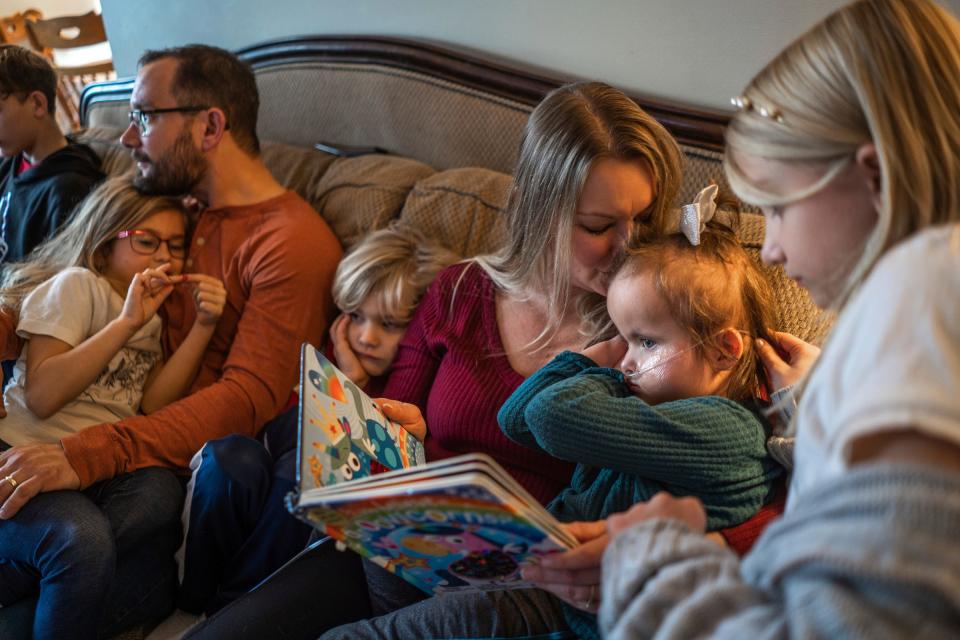 Jewel Calleja, of Livonia, kisses her daughter, CC Calleja, right, while sitting with (left to right), her son Colin Calleja, 11; daughter, Evelyn Calleja, 6; husband, Phil Calleja; son, Riley Calleja, 7, and daughter, Adelina Calleja, 9, in the living room of their home in Livonia on Dec. 22, 2023, while reading a book and watching television together. CC was born with Trisomy 18 and despite intense pressure to terminate the pregnancy, the Callejas say CC is now 4 years old and a valued and interactive member of the family.