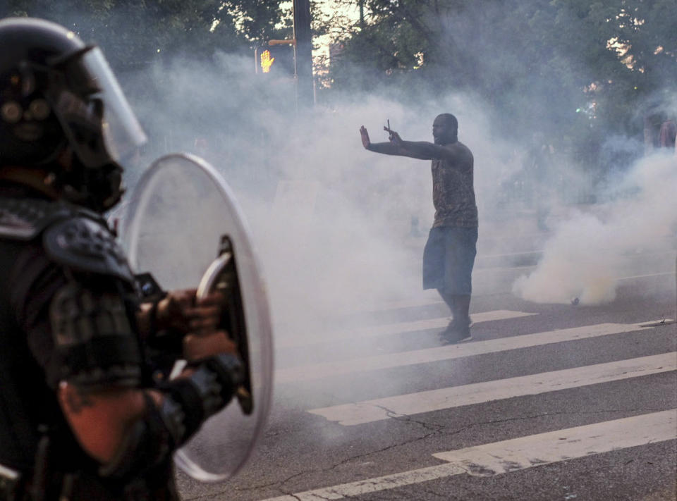 A protester tries to talk the police back amid tear gas in downtown Atlanta, Sunday, May 31, 2020. Protests continue across the country over the death of George Floyd, a black man who died after being restrained by Minneapolis police officers on May 25. (Ben Gray/Atlanta Journal-Constitution via AP)